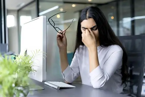 Woman experiencing eye strain from a computer screen.